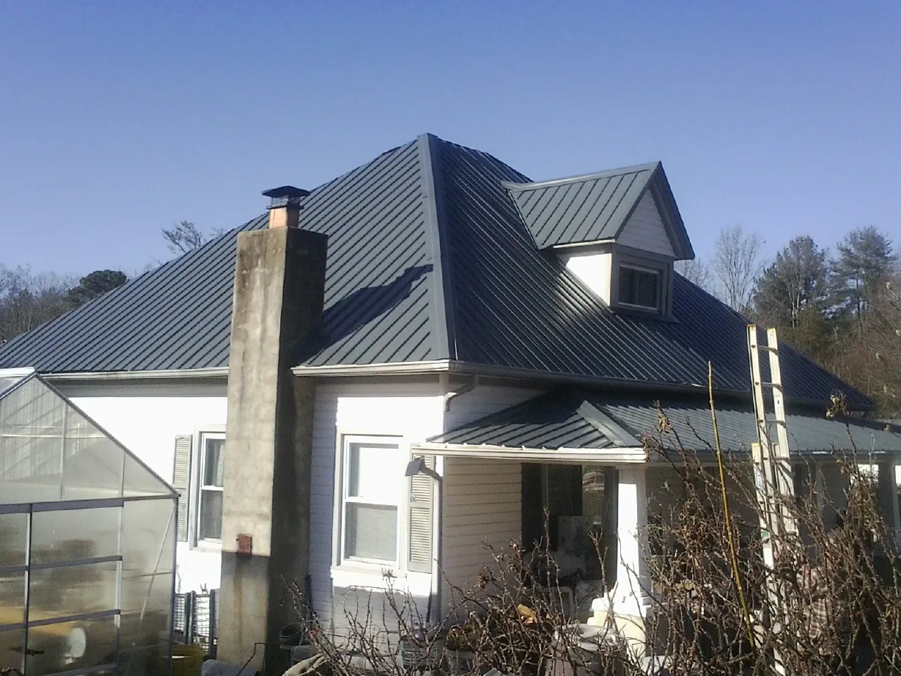Dark blue standing seam metal roof on a white farmhouse with dormer — Slate & Tile Roof Repair by Roofing Brothers in Shelbyville