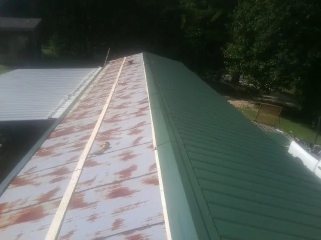 Old rusted panels beside newly installed green metal roofing — Wind Damage Roof Repair by Roofing Brothers in Shelbyville