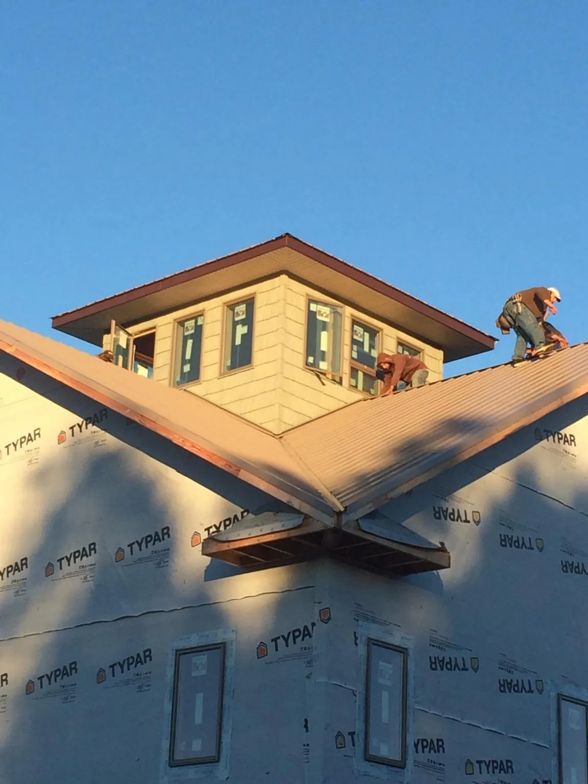 Roofers working around a rooftop cupola on a new metal roof at sunset — Roof Waterproofing in Shelbyville by Roofing Brothers